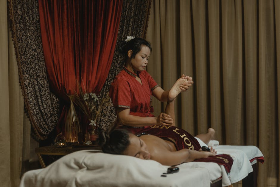 A woman receives a therapeutic massage from a professional masseuse in a calming spa environment.